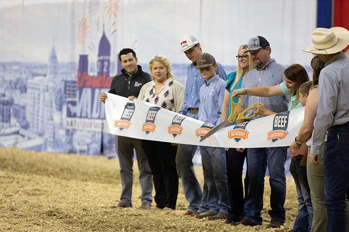 Bracie Cagle cuts the BEEF Academy ribbon July 5 in celebration of its launch during the NJAS in Madison, Wis. Pictured are (from left) Jimmy Stickley and Jaclyn Boester of the Angus Foundation; and Hadley Jordan, Collin Cagle, Jamie Cagle, David Cagle, Bracie Cagle and others with Ingram Angus; and representatives of the American Angus Association.