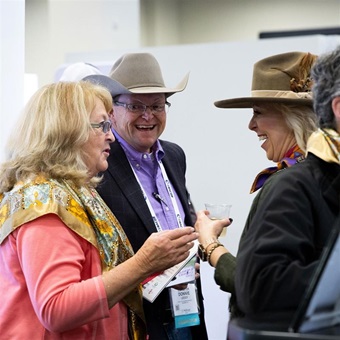 A group of women and men speaking together during a social hour at Angus Convention.