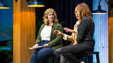 Two women talking on stage as presenters at a conference