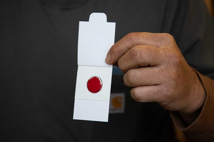 An individual holding up an appropriately collected DNA blood card sample.