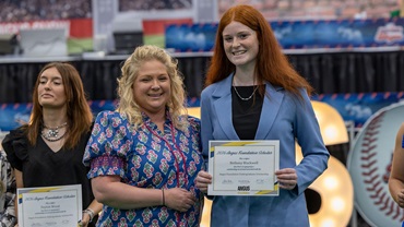 An Angus Foundation undergraduate scholarship recipient poses with a presenter while holding a scholarship certificate.