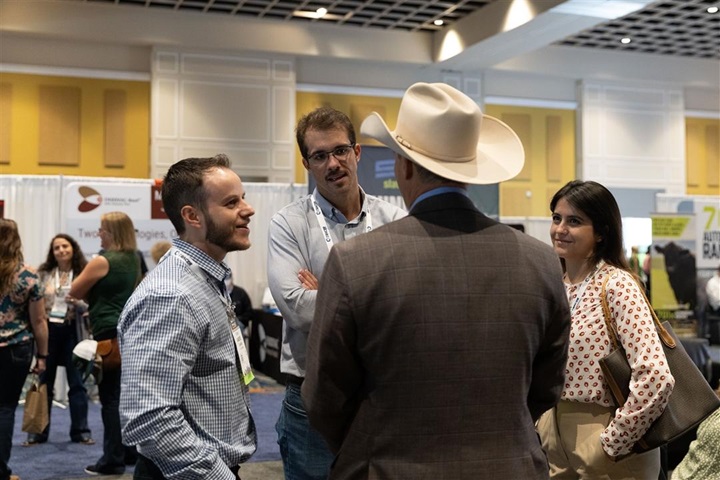 Three gentlemen and woman having conversation at a trade show