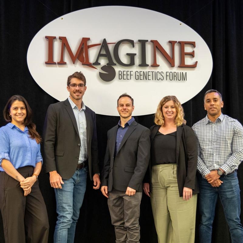 AGI staff members stand in front of the Imagine Conference signage.