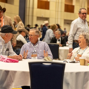Group of men sitting at a banquet table together talking.