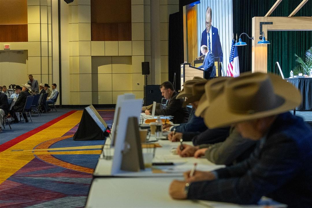 Ballot counters sit at a table at the front of a convention ballroom.