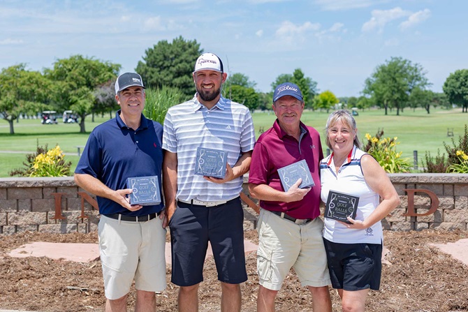 Group of three men and one woman on a golf tournament team.