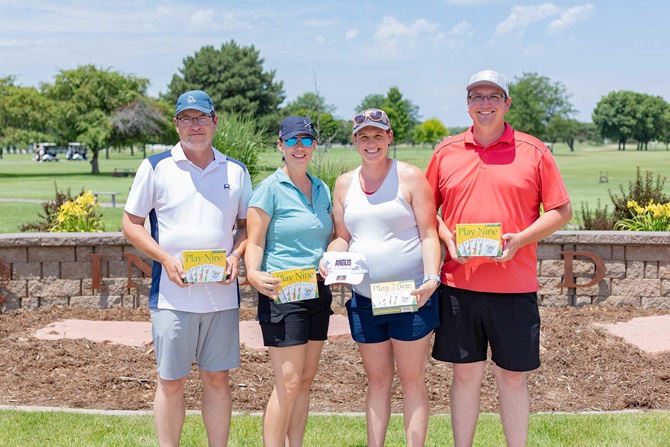 Group of two men and two women on a golf tournament team.