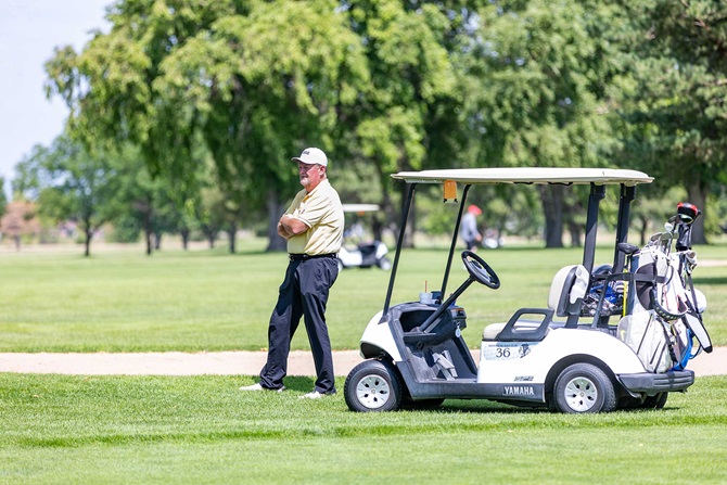 Man investigating course next to golf cart.