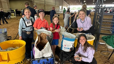 Junior members smile while displaying pop tabs collected for the Angus Impact service project alongside two NJAB representatives.