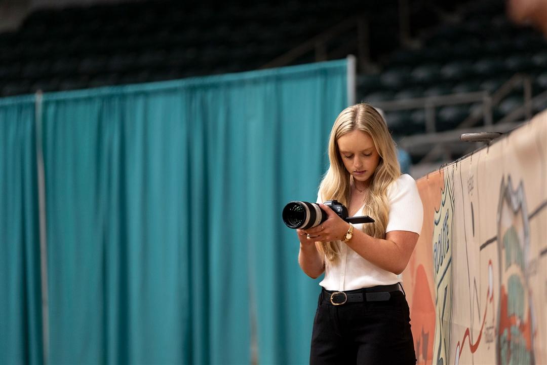 2025 Angus communications intern, Ashlyn Murdock, takes a ringside photo at the 2025 National Junior Angus Show event as part of her internship program.
