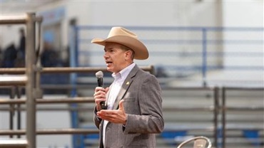 Man in a cowboy hat speaking on a mic.