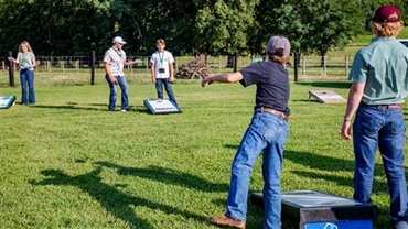 Kids playing a game of bean bag toss outside.