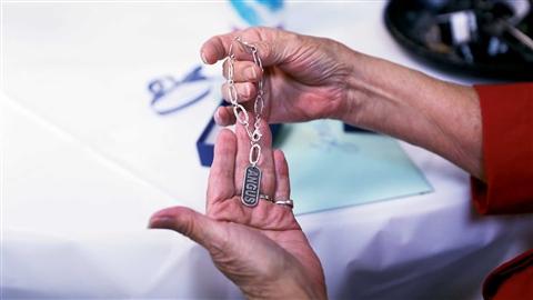 Hands hold a silver bracelet with an Angus charm attached