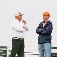 Two men in ball caps speaking to one another.
