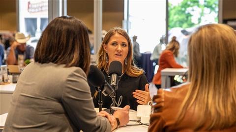 Three women sit around a table with microphones